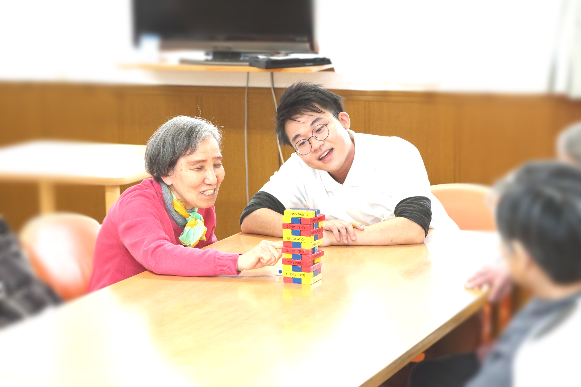 職員と入居者がジェンガで交流・レクリエーション中の様子